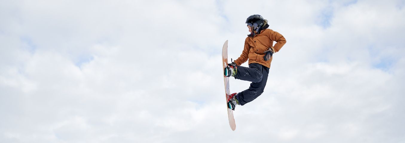 Mężczyzna wykonujący skok na desce snowboardowej