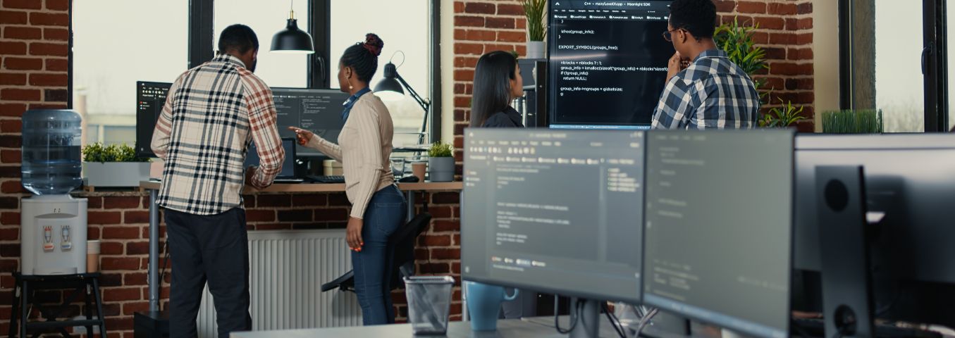 Zespół programistów i programistek omawia pracę na ekranach komputerów