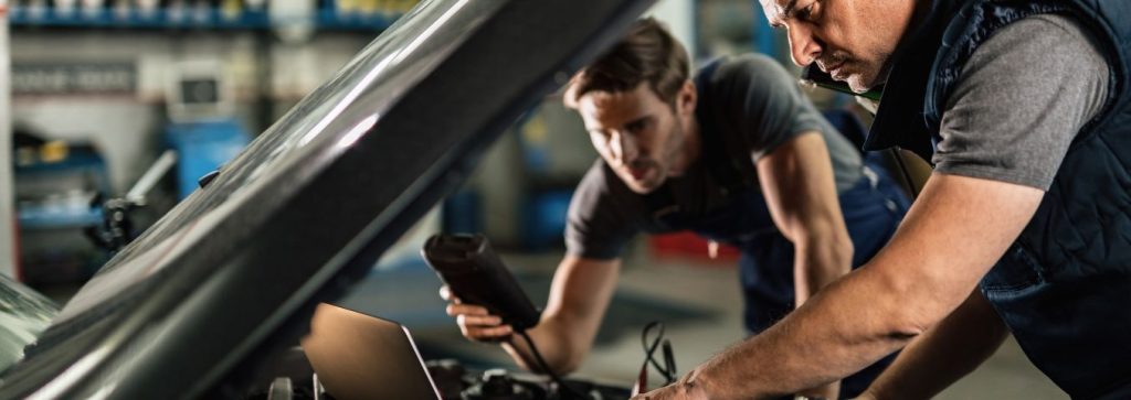 Mechanicy przeprowadzający diagnostykę elektroniczną auta w warsztacie