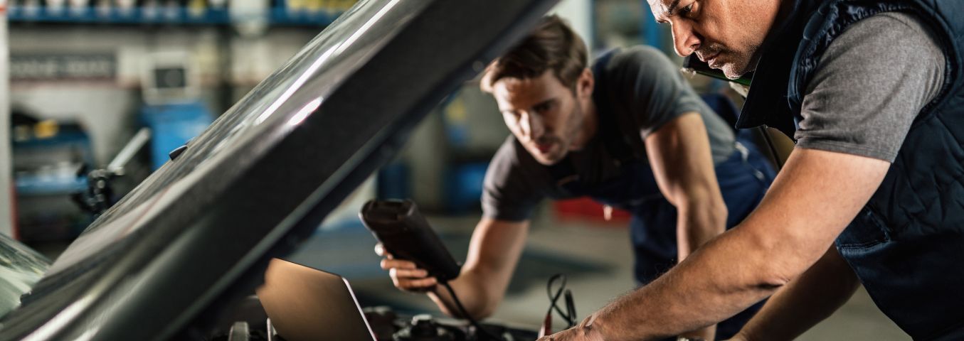 Mechanicy przeprowadzający diagnostykę elektroniczną auta w warsztacie