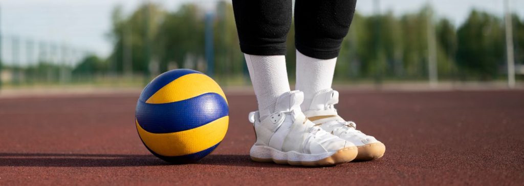 Piłka i nogi siatkarki na tle boiska