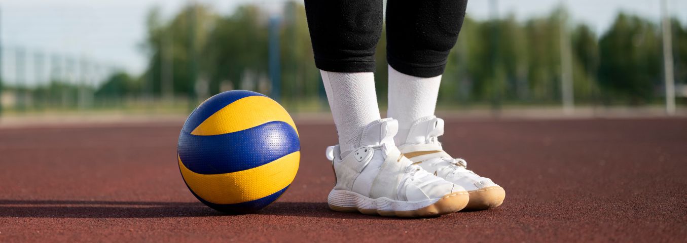 Piłka i nogi siatkarki na tle boiska