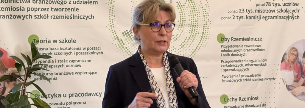 Agnieszka Marszałek - liderka projektu „Prowadzenie i rozwój Zintegrowanego Rejestru Kwalifikacji” przemawia do uczestników obchodów „Dnia Pracownika Publicznych Służb Zatrudnienia”. Stoi na scenie na tle godła polskiego