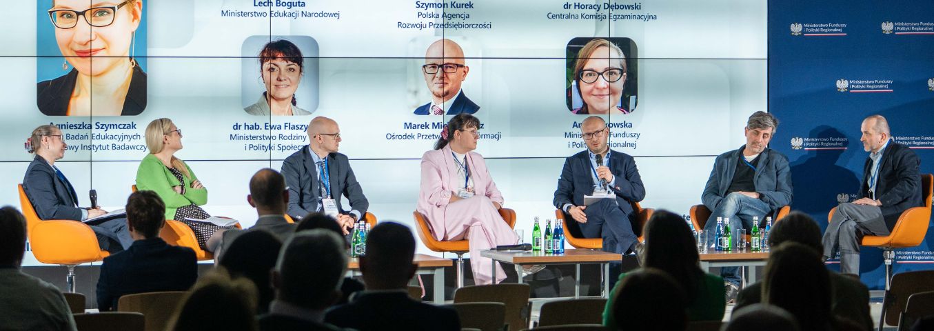 Osoby na scenie rozmawiające podczas konferencji