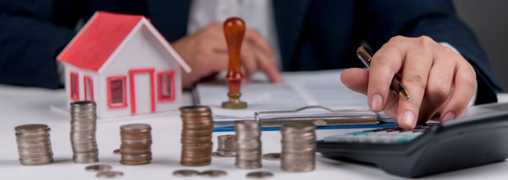 Model domu i stosy monet na stole