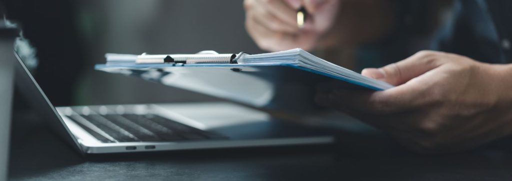 Dłonie przy klawiaturze z dokumentami