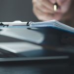 Dłonie przy klawiaturze z dokumentami